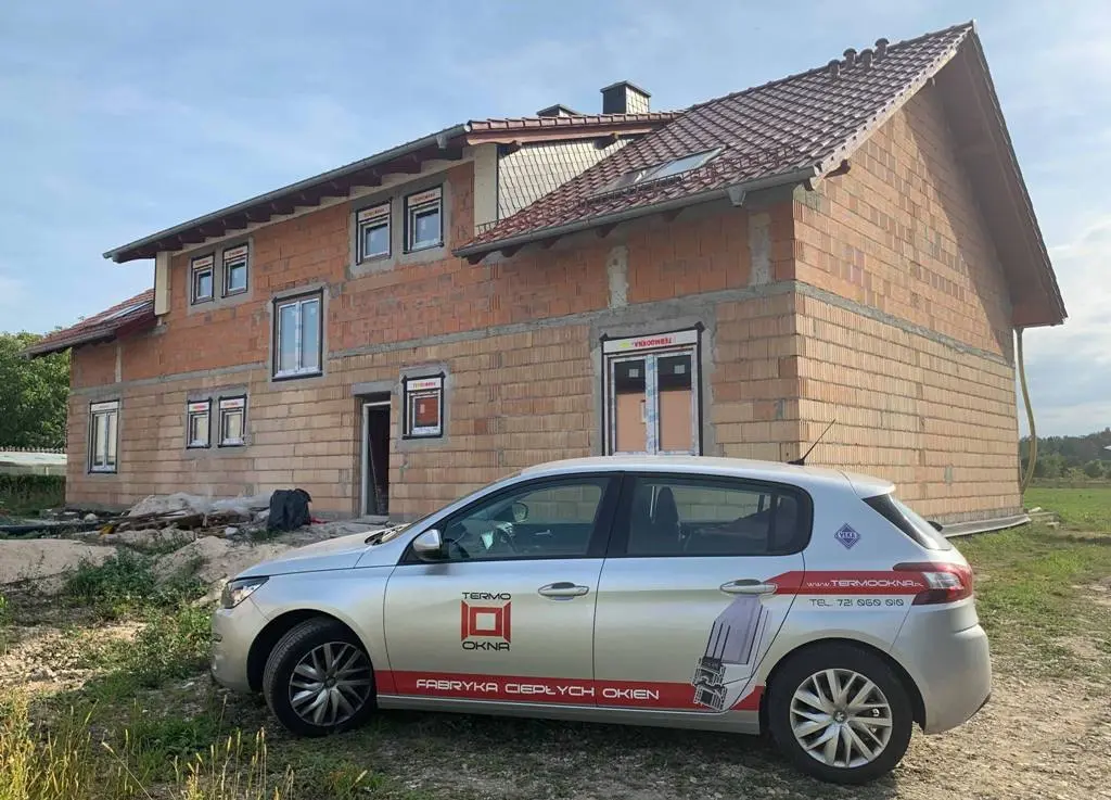 Dom w stanie surowym z zamontowanymi oknami i samochodem Termookna